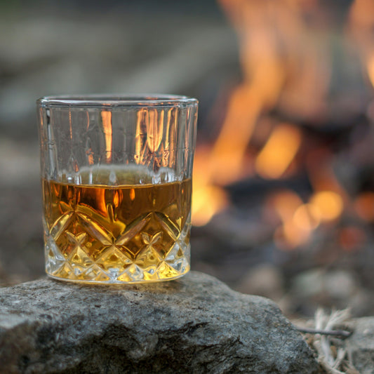 Glass of bourbon by a bonfire