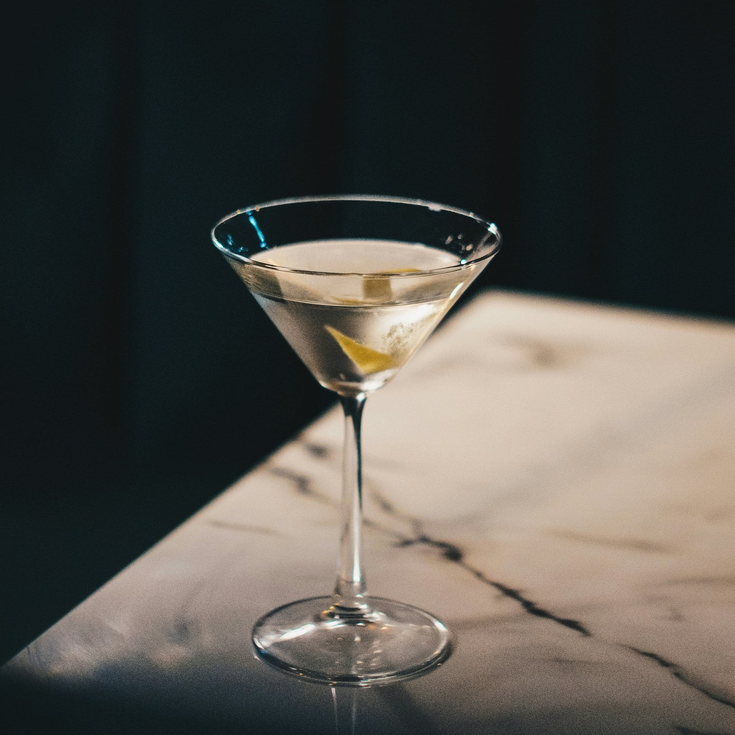 Cocktail in a martini glass on a dark surface