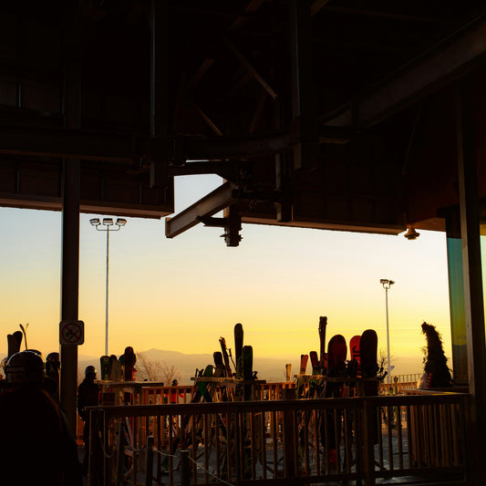Sunset view from a high vantage point with skis and people silhouetted against the sky.